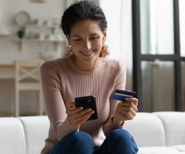 smiling woman using her phone to make an online credit card payment