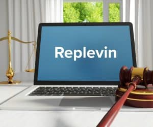 Replevin displaying on a laptop screen with a gavel block and scale placed on a white table